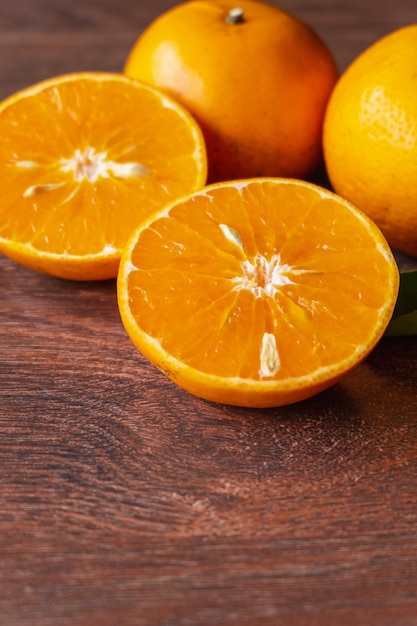 Frutas frescas de laranja e laranja cortadas ao meio em uma mesa de madeira