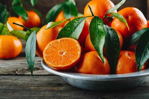 Frutas frescas de tangerina Clementina ou tangerinas com folhas em fundo rústico de madeira