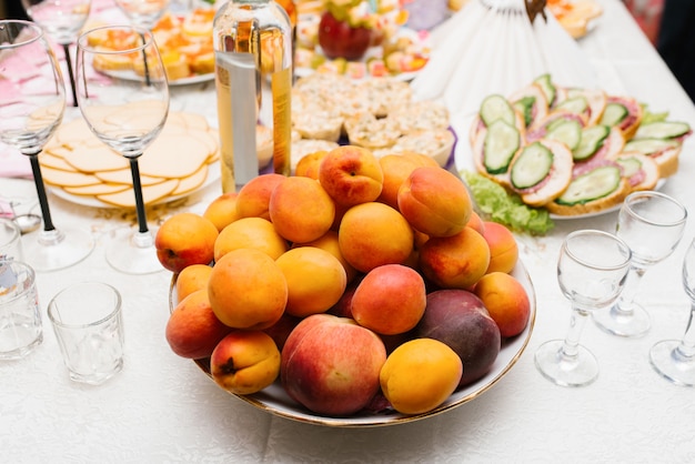 Frutas frescas duraznos, albaricoques y ciruelas en un plato en la mesa de vacaciones