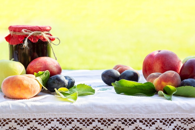 Frutas frescas duraznos, nectarinas, ciruelas y tarros caseros de mermelada