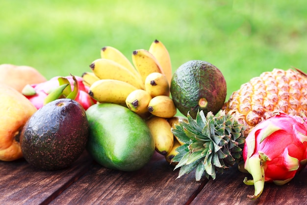 Frutas frescas. Frutas exóticas mixtas sobre fondo de madera. Alimentación saludable, dieta. Vista superior con espacio de copia de hierba