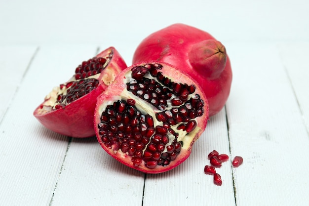 Frutas frescas de la granada aisladas en un fondo de madera blanco.