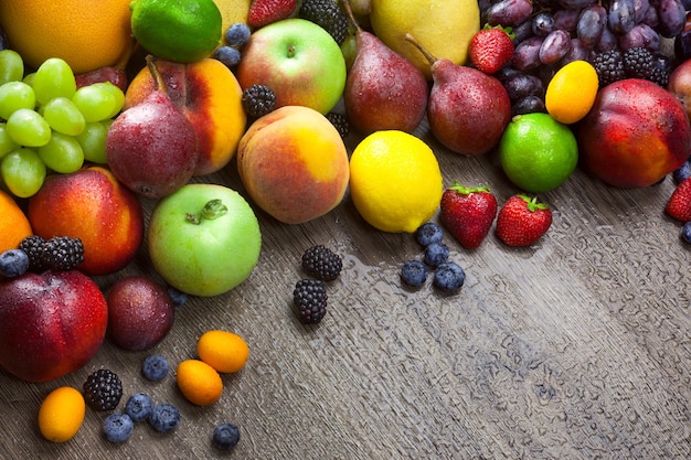 Frutas frescas mezcladas en el fondo de madera con gotas de agua