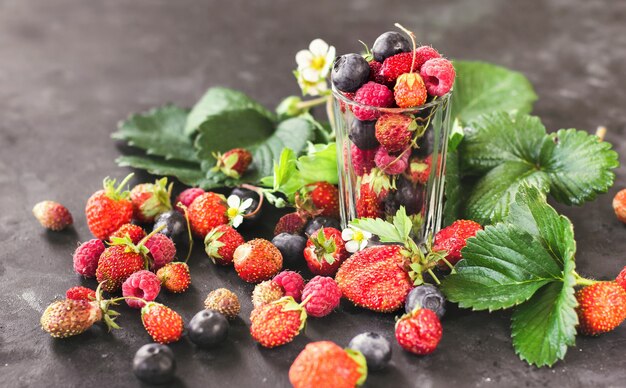 Frutas frescas, morangos, framboesas e mirtilos em um fundo escuro colheita de verão bagas a.