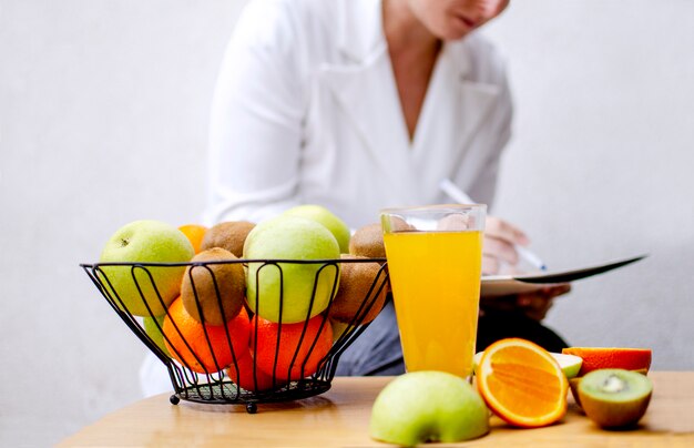 Foto frutas frescas na mesa e nutricionista escrever receita para uma alimentação saudável durante o surto de coronavírus