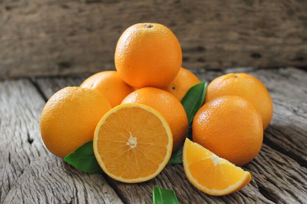 Frutas frescas de naranja con hojas sobre mesa de madera