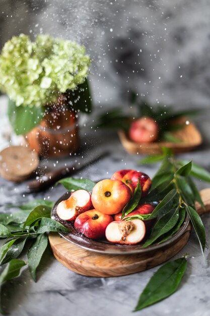 Frutas frescas pêssegos com folhas em um close-up de placa.