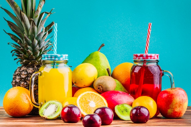 Foto frutas frescas saudáveis e suco mason frascos na mesa contra o fundo azul