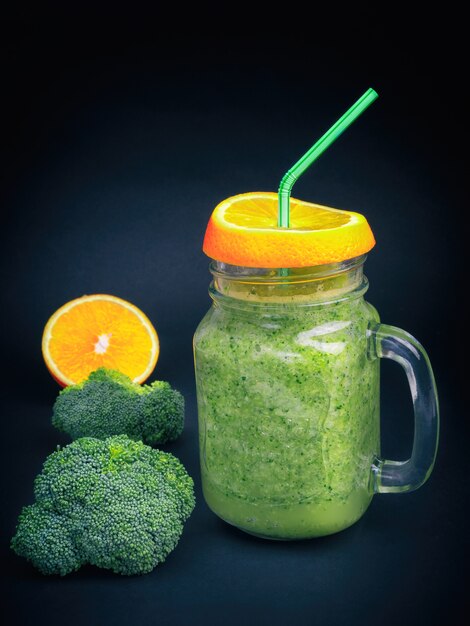 Foto frutas frescas vegetais brócolis aipo laranja smoothie garrafa agitar preto escuro