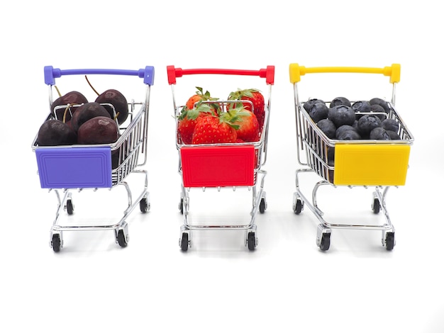 Foto frutas frescas del verano en el carro de la compra o la carretilla aislada en el fondo blanco.