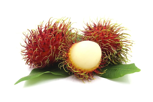 Foto frutas y hojas de rambután sobre fondo blanco.