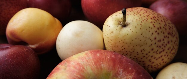 Frutas jugosas en una mesa de madera vieja. Manzanas, peras, ciruelas, albaricoques, de cerca.