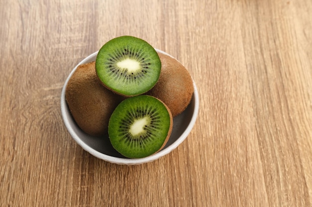 Frutas de kiwi frescas servidas en un tazón blanco sobre fondo de madera imagen de enfoque seleccionada de cerca