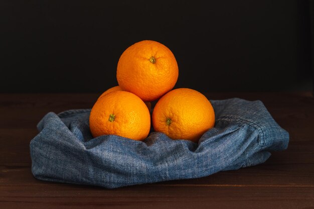 Frutas laranjas perto de têxteis de denim no quadro escuro Conceito mínimo de frutas suculentas laranja cítricas