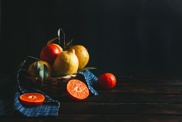 Frutas limão e laranja, localizadas em uma cesta em uma mesa de madeira rústica