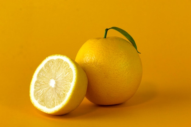 Frutas de limón orgánico y una rodaja de limón con hoja aislada sobre fondo amarillo