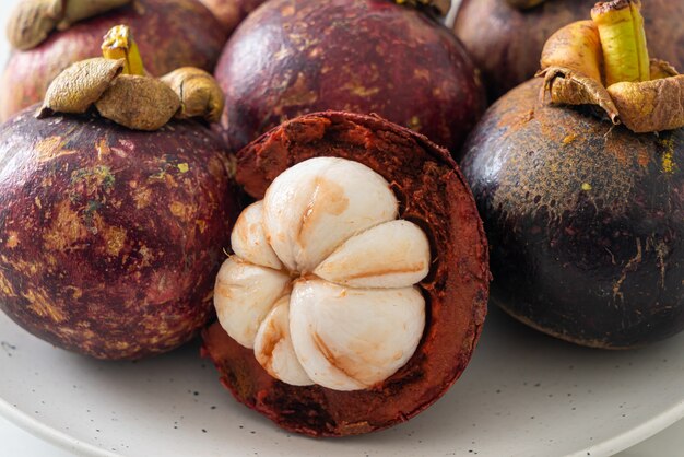 Frutas maduras frescas del mangostán en la placa blanca.