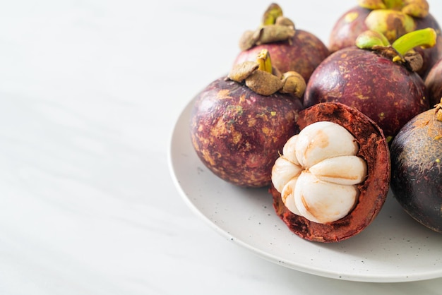 Frutas maduras frescas del mangostán en la placa blanca.