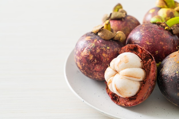 Frutas maduras frescas del mangostán en la placa blanca.