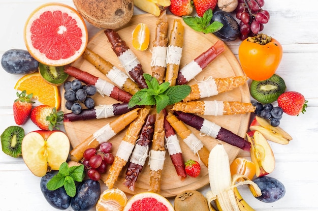 Frutas maduras variadas e batatas fritas secas em fundo cinza