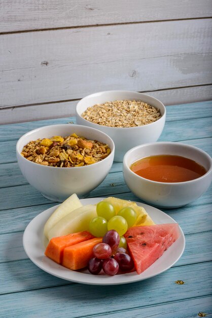 Frutas, miel, avena y granola en mesa de madera azul Comida sana