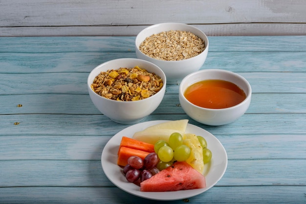 Frutas, miel, avena y granola en mesa de madera azul Comida sana