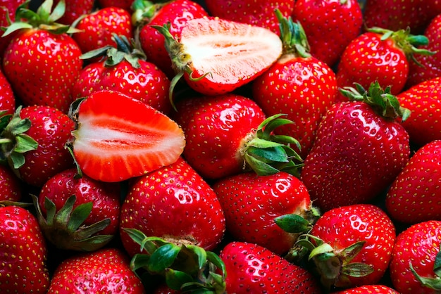 Las frutas orgánicas naturales frescas de la fresa con las hojas verdes se cierran encima de fondo.