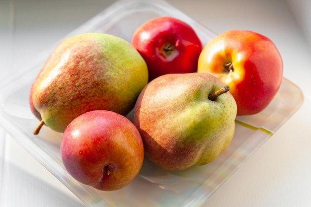 Frutas de otoño en un plato Peras, manzanas y ciruelas se apilan en un plato Alimentos orgánicos saludables