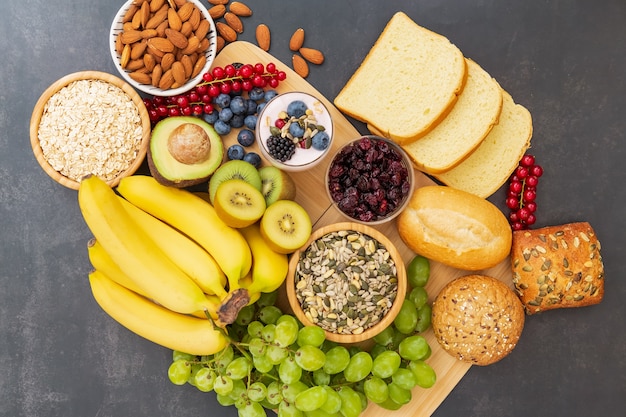 Frutas y pan, cereales integrales y nueces sobre mesa de madera