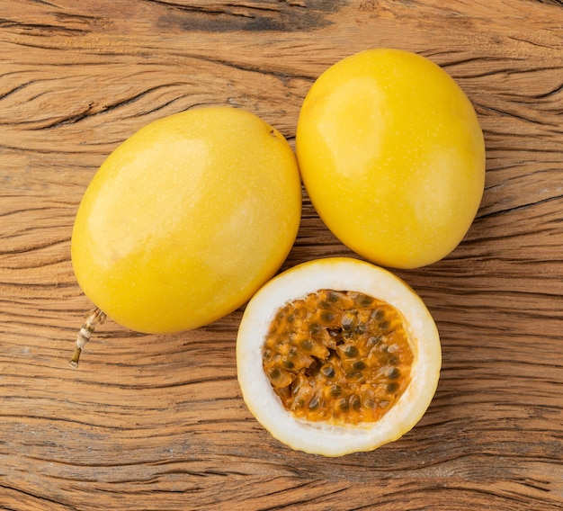 Frutas de la pasión con fruta cortada sobre mesa de madera