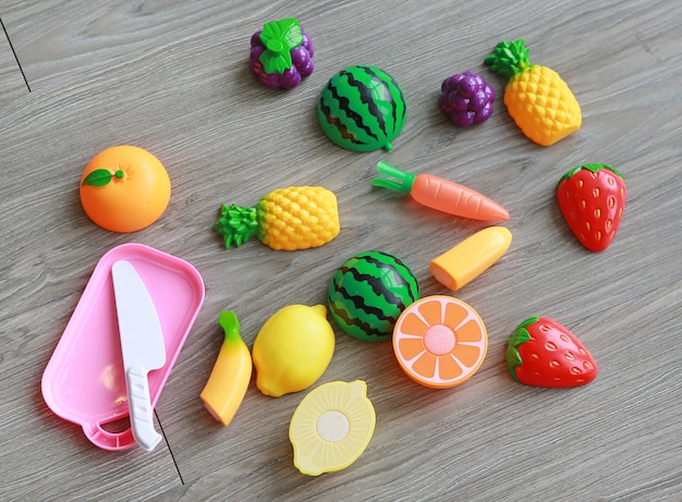 Frutas plásticas sobre fondo de madera, juguete infantil.