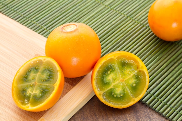 Frutas y rodajas de lulo o naranjilla sobre la mesa de madera Solanum quitoense