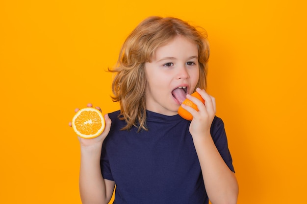 Frutas saludables para niños Niño comer naranja en estudio Retrato de estudio de niño lindo lamer naranja aislado sobre fondo amarillo