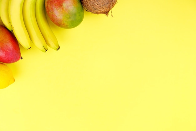 Foto frutas sazonais de verão tropical suculento maduro manga coco kiwi bananas morangos em fundo amarelo.