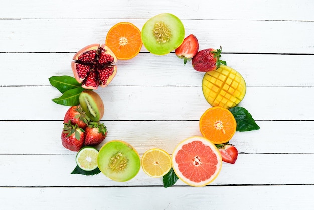 Frutas sobre un fondo blanco de madera Mango melón granada fresa plátano Vista superior Espacio libre para su texto