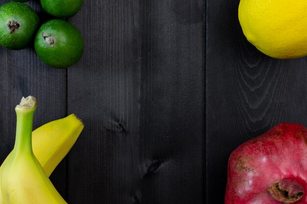 Frutas sobre un fondo de madera. Granada, limón, feijoa, plátano.