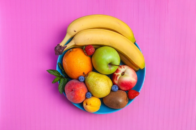 Frutas suculentas brilhantes dispostas em um prato - mirtilos, bananas, peras, maçãs, hortelã