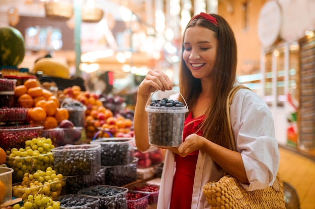 Frutas suculentas. Mulher fofa comprando frutas e parecendo animada