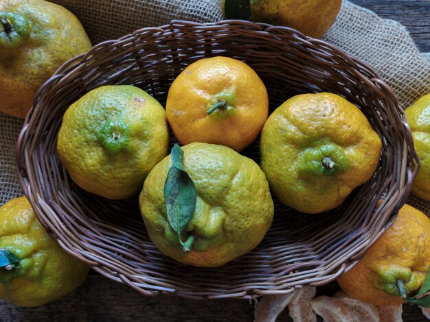 Frutas tangerinas na cesta em fundo de madeira rústico.