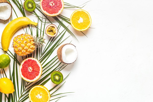 Frutas tropicais e folhas de palmeira em um fundo branco