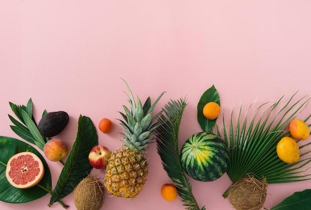 Frutas tropicais e folhas em uma vista superior de fundo rosa