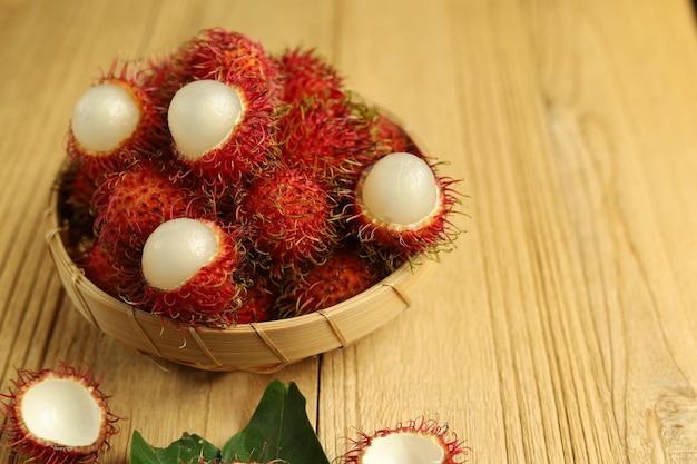 Frutas tropicais frescas de rambutan em uma cesta com fundo de madeira