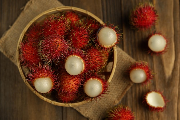 Frutas tropicais frescas de rambutan em uma cesta com fundo de madeira