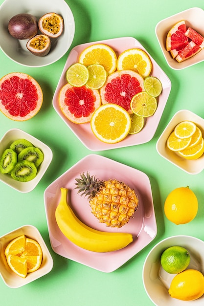 Foto frutas tropicais inteiras e fatias em pratos, vista superior.