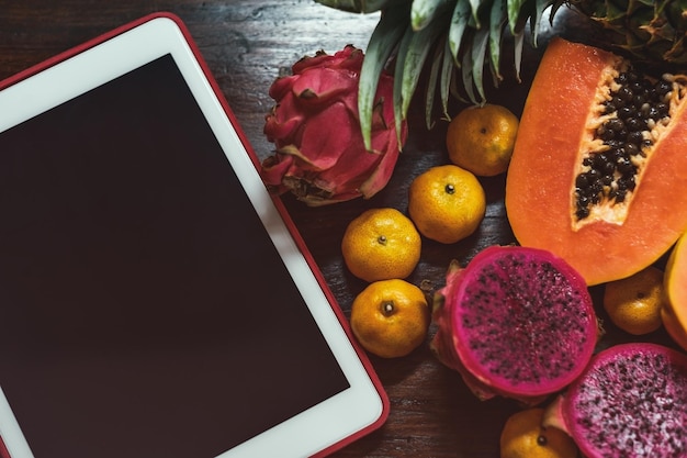 Frutas tropicais perto de laptop moderno em fundo de madeira Estilo de vida vegano