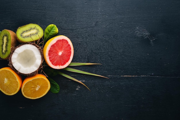 Frutas Tropicales Frescas. Coco, naranja, kiwi y pomelo. Sobre un fondo de madera. Vista superior. Espacio libre para texto.