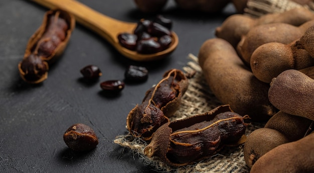 Frutas tropicales Frijoles de tamarindo con cáscara en un bloque de carnicero marrón sobre un fondo oscuro lugar de receta de menú de banner de fruta saludable para la vista superior de texto