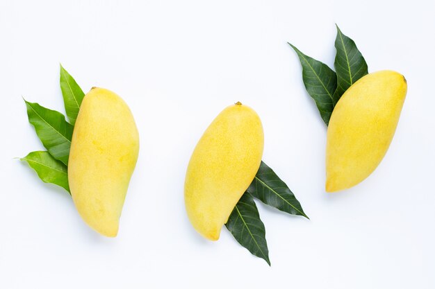 Frutas tropicales, mangos con hojas sobre superficie blanca