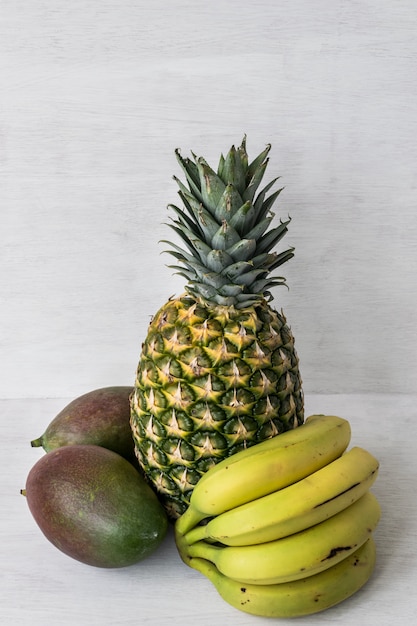 Foto frutas tropicales: piña, mango y plátanos. fondo blanco con espacio para copiar texto