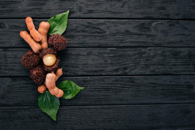 Frutas tropicales de rambután y tamarindo sobre un fondo de madera Vista superior Espacio de copia